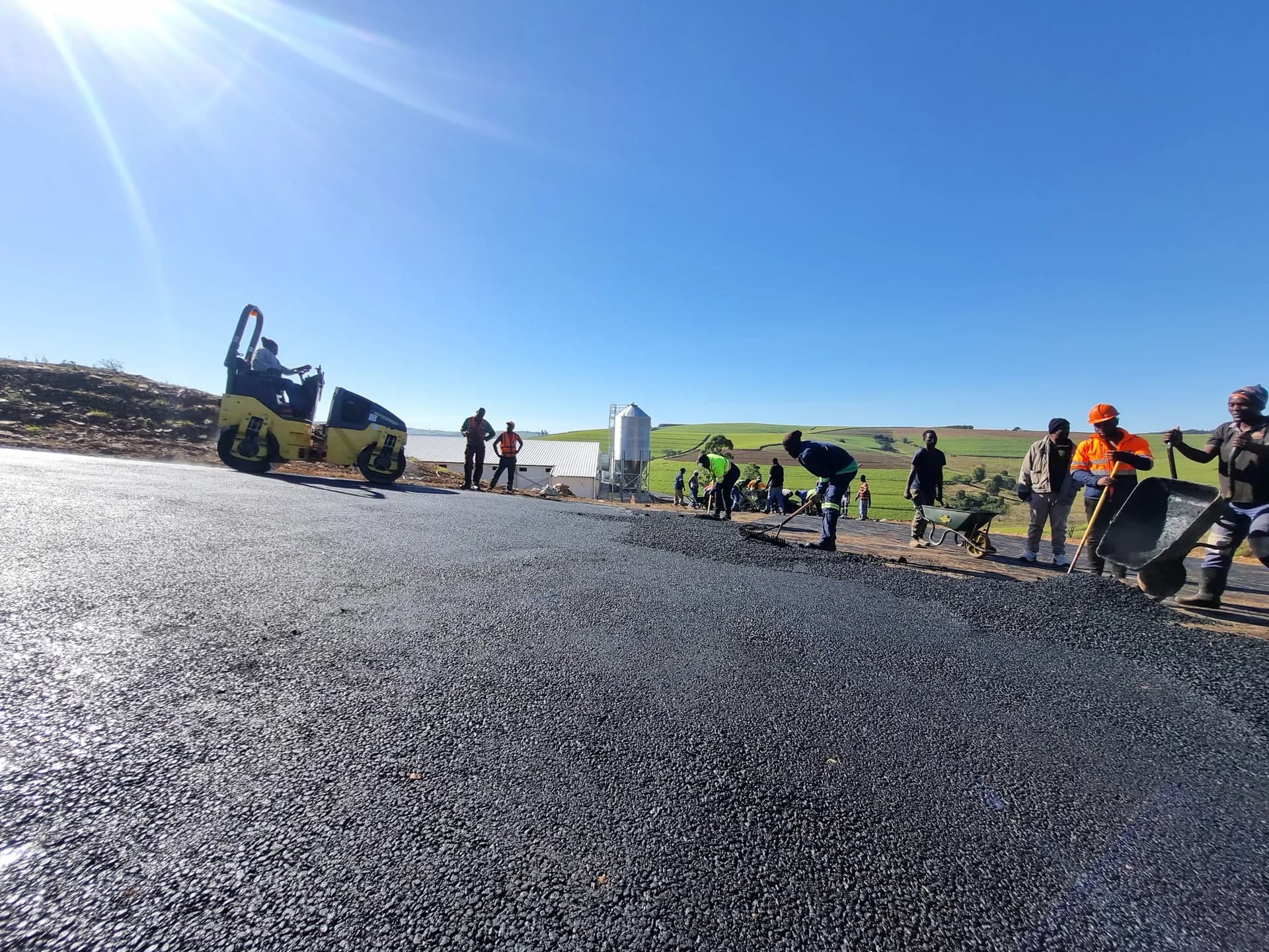 Newly surfaced asphalt road with the crew finishing the edges