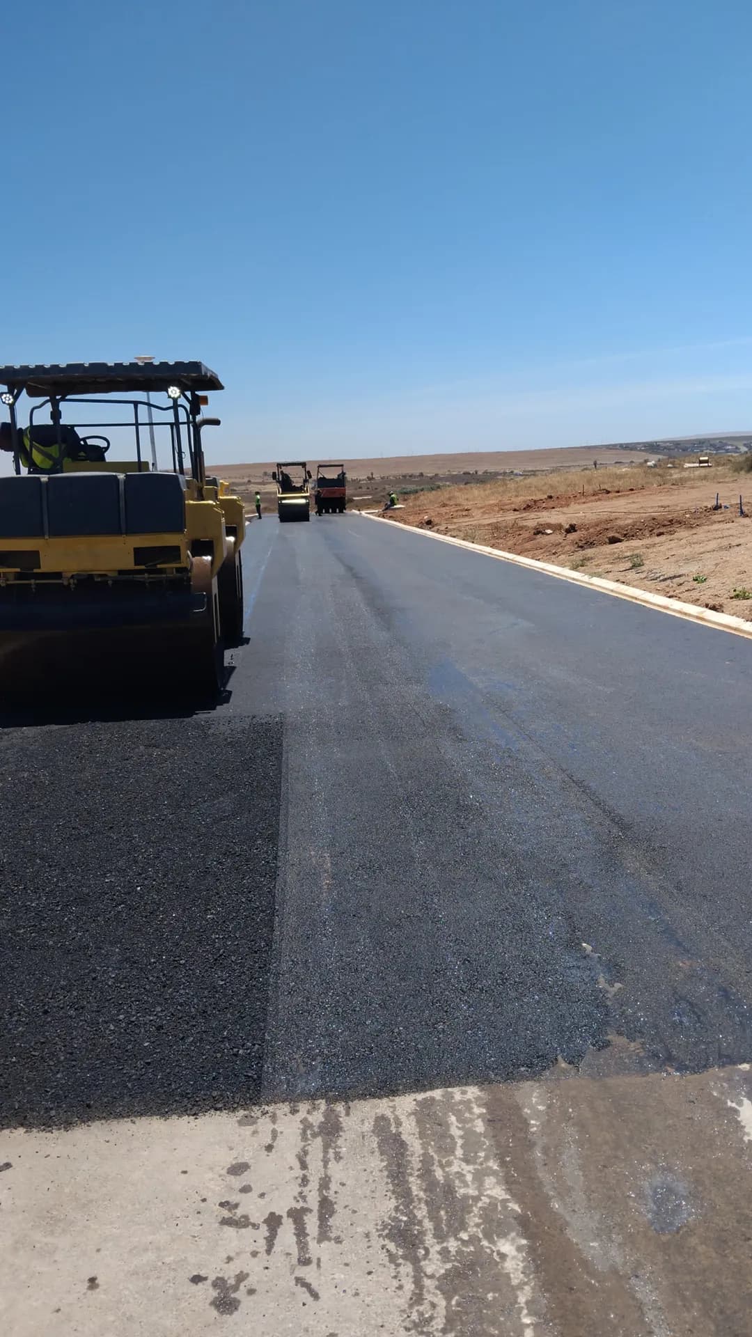 Newly surfaced residential street with paving plant behind